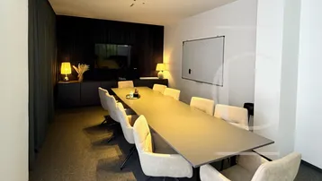 Geräumiger Konferenzraum mit langem Tisch, bequemen Stühlen und modernem Design für Besprechungen.
