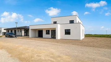 Modernes, weißes Einfamilienhaus im Neubaugebiet mit minimalistischer Architektur und flachem Dach.