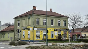 Gebäude an einer Straßenecke mit Geschäften im Erdgeschoss und Wohnungen darüber.