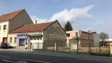Blick auf die Straße mit angrenzenden Gebäuden und einem Bestattungsunternehmen unter blauem Himmel.