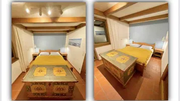 Gemütliches Schlafzimmer mit Holzbalkendecke, Terrakottaboden und traditioneller Truhe als Blickfang.