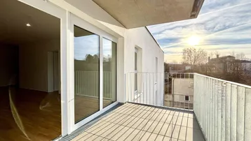 Sonniger Balkon mit Fliesenboden und Blick auf die Umgebung bei Sonnenuntergang.