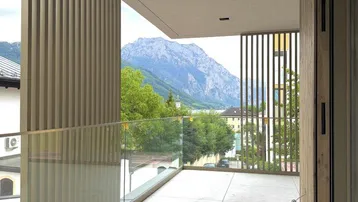 Geräumiger Balkon mit Glasbrüstung, Holzverkleidung und beeindruckendem Bergblick.