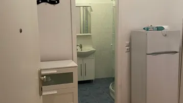 Heller Flur mit Holzfußboden, weißer Kommode und Blick in das Badezimmer.