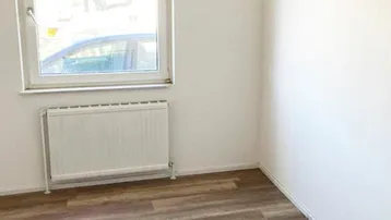 Heller Raum mit großem Fenster, Heizkörper und Laminatboden, ideal als Schlaf- oder Arbeitszimmer.