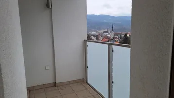 Kleiner Balkon mit Fliesenboden und Blick auf die Stadt und eine historische Kirche.