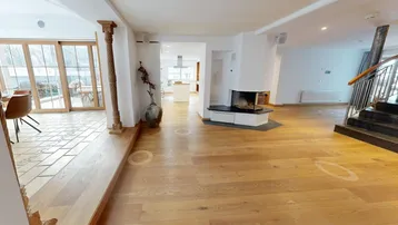 Geräumiger offener Wohnbereich mit Kamin, Holzfußboden und Treppe.