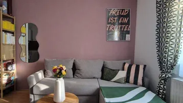 Gemütliches Wohnzimmer mit beiger Couch, Holztisch und farbiger Akzentwand.