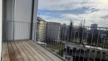 Geräumiger Balkon mit Holzboden und Metallgeländer, bietet einen weiten Blick über die Stadt.