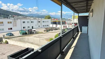 Langer überdachter Balkon mit Blick auf die Umgebung und die Berge.