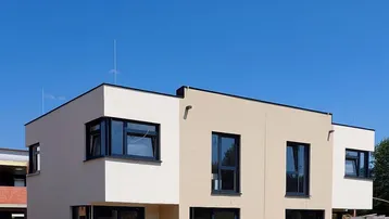 Modernes Doppelhaus mit heller Fassade und großen Fenstern auf grünem Rasen.