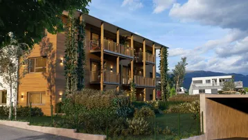 Moderne Wohnanlage mit Holzfassade, Balkonen und begrüntem Außenbereich unter blauem Himmel.