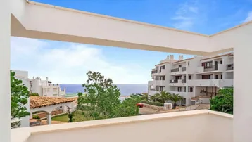 Panoramablick vom Balkon auf das Meer und die umliegenden Gebäude unter blauem Himmel.