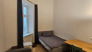 Helles Schlafzimmer mit Einzelbett, Schreibtisch und Holzboden, ideal für Studenten oder Einzelpersonen.