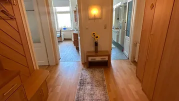 Heller Flur mit Holzmöbeln, einem Teppichläufer und Zugang zu verschiedenen Zimmern.