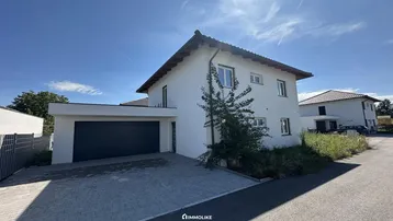 Modernes Einfamilienhaus mit Satteldach, weißer Fassade und integrierter Garage.