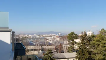 Panoramablick über die Stadt mit Bergen im Hintergrund unter klarem blauem Himmel.