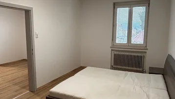 Schlafzimmer mit Laminatboden, einem Bett und Fenster, das eine angenehme Atmosphäre schafft.