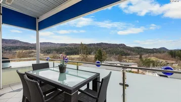 Möblierter Balkon mit Esstisch und Stühlen, bietet einen weiten Blick auf die grüne Landschaft.