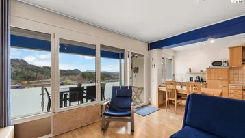 Heller Wohn- und Essbereich mit Holzboden, Zugang zum Balkon und integrierter Küche.
