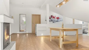 Offener Wohnbereich im Dachgeschoss mit Kamin, Holzboden und moderner Beleuchtung.