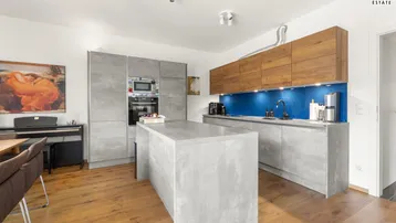 Moderne Küche mit grauen Fronten, Holzdetails, Kücheninsel und blauer Rückwand.
