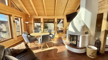 Gemütlicher Wohn-Essbereich mit Holzelementen, Kamin und großen Fenstern für viel Tageslicht.