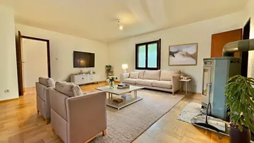 Gemütliches Wohnzimmer mit Kaminofen, bequemen Sofas und hellem Parkettboden.