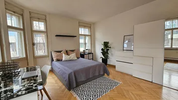 Helles Schlafzimmer mit Fischgrätparkett, großzügigen Fenstern und modernem Schreibtischbereich.