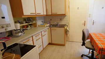 Funktionale Küche mit älteren Einbaumöbeln, Essbereich und Gastherme.