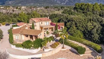 Eine beeindruckende Villa mit großem Pool und weitläufigem Grundstück, umgeben von Bergen und üppiger Vegetation.