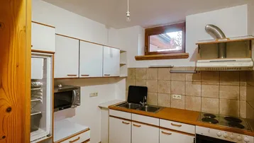 Kleine, funktionale Küche mit weißen Schränken, Holztheke und grundlegenden Geräten.
