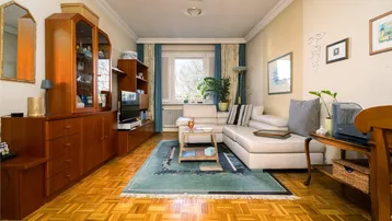 Gemütliches Wohnzimmer mit Parkettboden, beiger Couch und Holzmöbeln, ideal zum Entspannen.