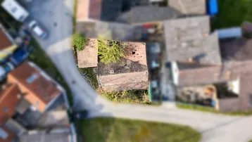 Luftaufnahme eines Grundstücks mit Bestandsgebäude und umliegenden Häusern in ländlicher Umgebung.