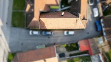 Luftaufnahme eines Wohnhauses mit Ziegeldach und umliegenden Gebäuden in einer Siedlung.