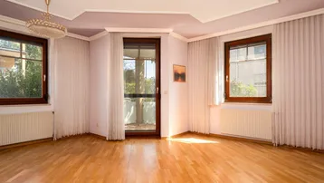 Helles Wohnzimmer mit Parkettboden, Stuckdecke und Zugang zum Balkon.