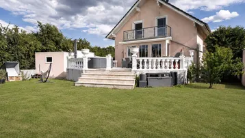 Großzügiger Gartenbereich mit Rasenfläche und einer erhöhten Terrasse mit Whirlpool.