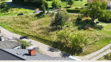 Großes Grundstück in ländlicher Umgebung mit viel Grün, Bäumen und angrenzender Straße.