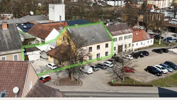 Luftaufnahme des Anwesens mit umliegender Bebauung und Parkplätzen, das Gebäude ist grün umrandet.