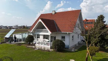 Freistehendes Einfamilienhaus mit Garten, Terrasse und Solaranlage auf dem Dach.