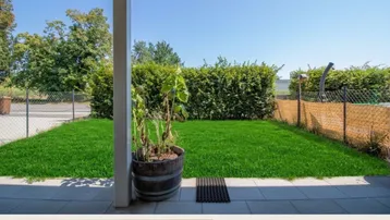 Kleiner, gepflegter Gartenbereich mit Rasenfläche und gepflasterter Terrasse, ideal zum Entspannen im Freien.