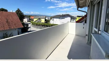 Heller Balkon mit Fliesenboden und weitem Blick über die Nachbarschaft und entfernte Berge.