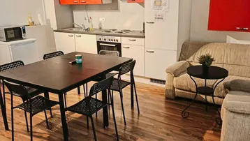Offener Wohn-Essbereich mit integrierter Küche, Esstisch und Sofa, ideal für geselliges Beisammensein.