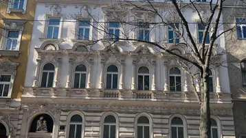 Historische Fassade eines Wiener Wohnhauses mit reich verzierten Fenstern und Balkonen.