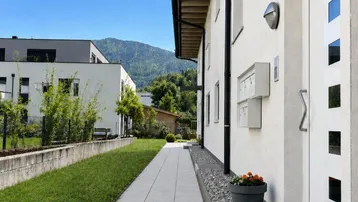Moderner Eingangsbereich eines Hauses mit gepflegtem Vorgarten und Gehweg.