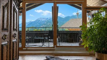 Helles Wohnzimmer mit Holzboden, antiken Möbeln und Panoramafenstern mit Bergblick.