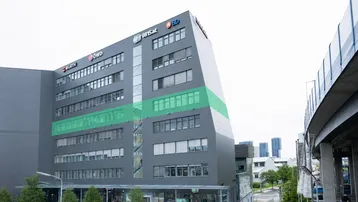 Modernes Bürogebäude mit markanter Architektur und großen Fensterfronten, die Fassade ist in Grau gehalten.