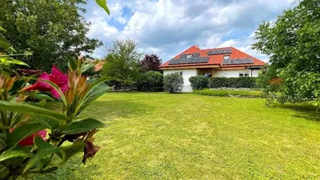 Großzügiger Gartenbereich mit gepflegtem Rasen und Blick auf das Wohnhaus mit Solaranlage.