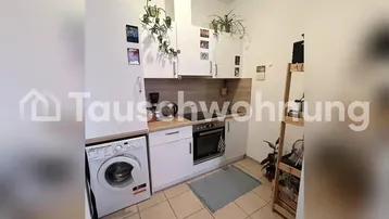 Kleine Küche mit weißen Schränken, Holzarbeitsplatte, integriertem Backofen und Waschmaschine.