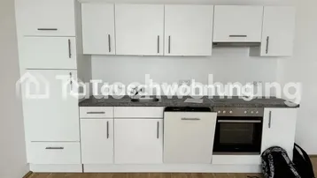 Moderne Einbauküche mit weißen Schränken, grauer Arbeitsplatte und integrierten Geräten.